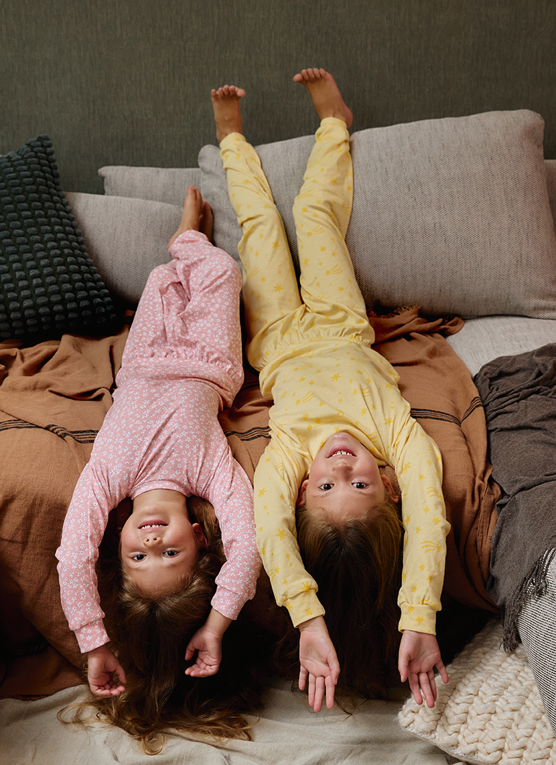 Devojčice leže na krevetu u žutoj i roze pidžami na dug rukav