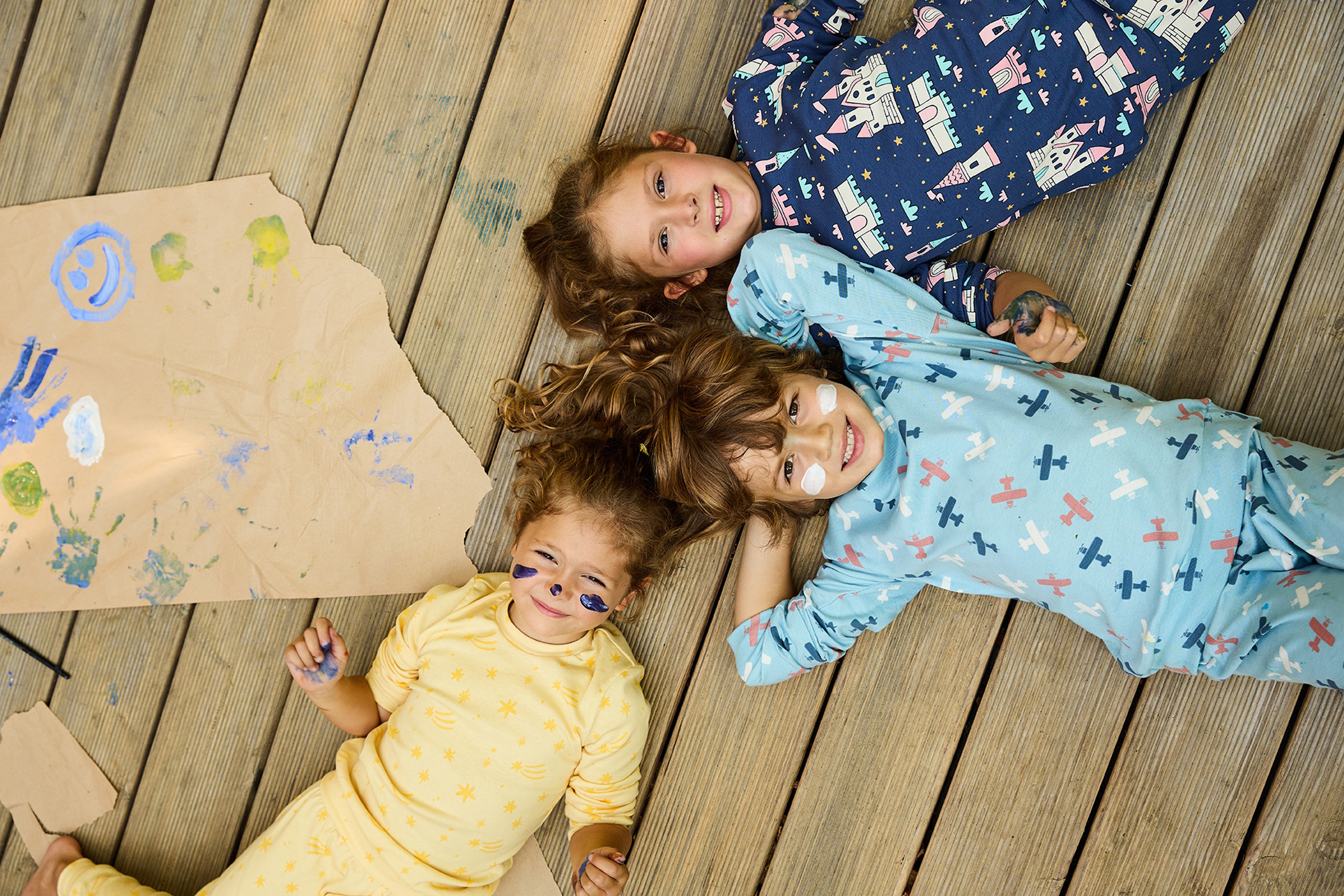 Dečak i dve devojčice leže napolju u šarenim pidžamama na dug rukav