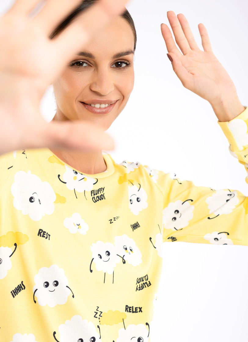 Žena stoji u žutoj pidžami sa oblacima na dug rukav 