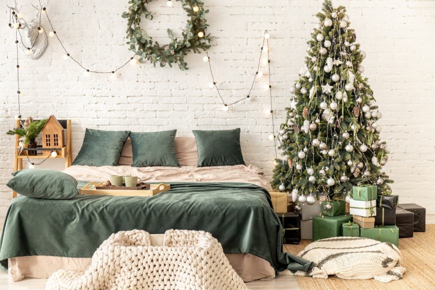 Krevet sa zelenim jastucima i okićena jelka sa zlatnim ukrasima
