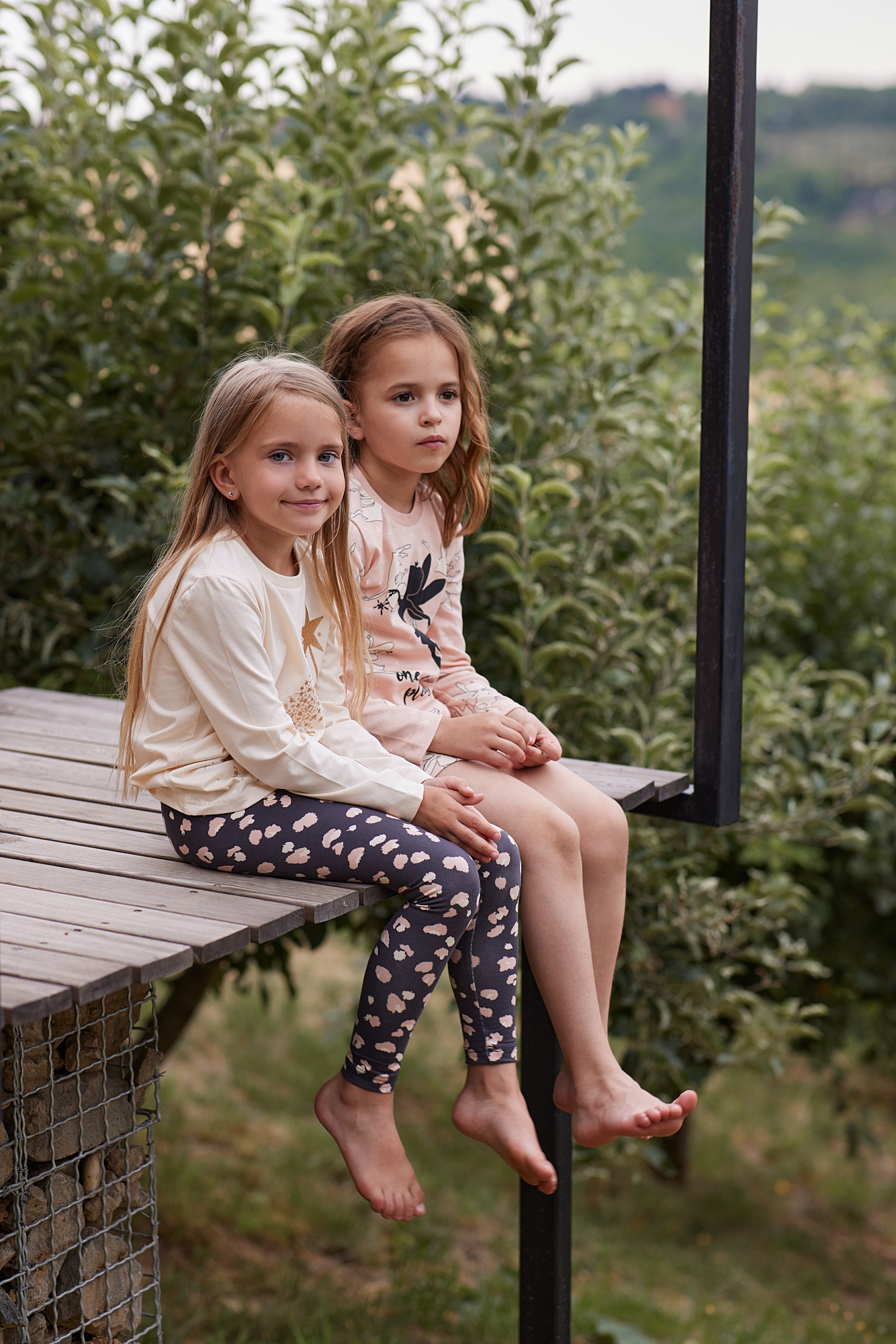 Dve devojčice u bež pidžamama sede na terasi