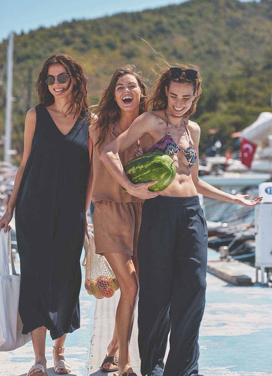 Tri devojke u letnjoj odeći nose voće