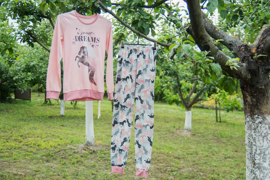 dečija dugačka pidžama u roze boji visi na drvetu