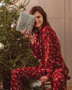 Žena drži poklon i nosi pidžamu sa novogodišnjim motivima