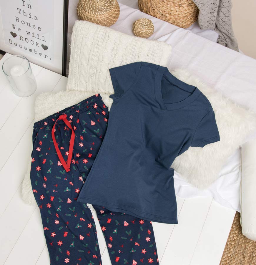 Gornji i donji deo odeće za spavanje u teget boji na krevetu pored peškira