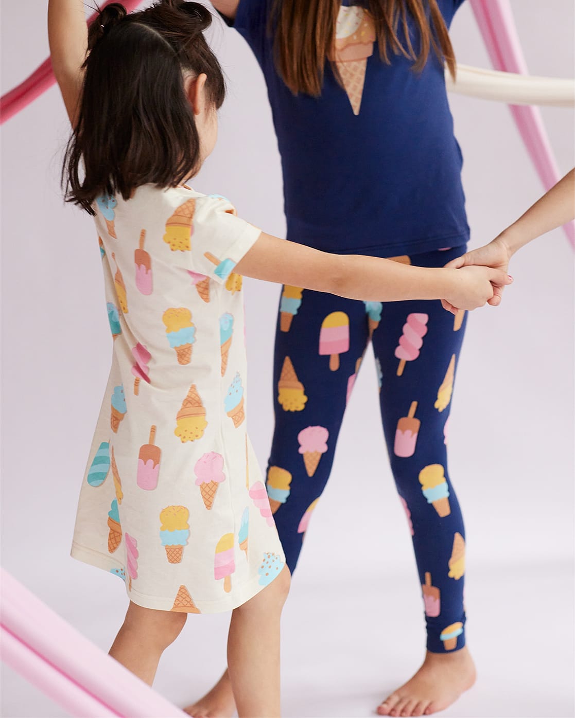 Dve devojčice se vrte u krug, u beloj spavaćici sa motivom sladoleda i plavoj pidžami sa motivom sladoleda