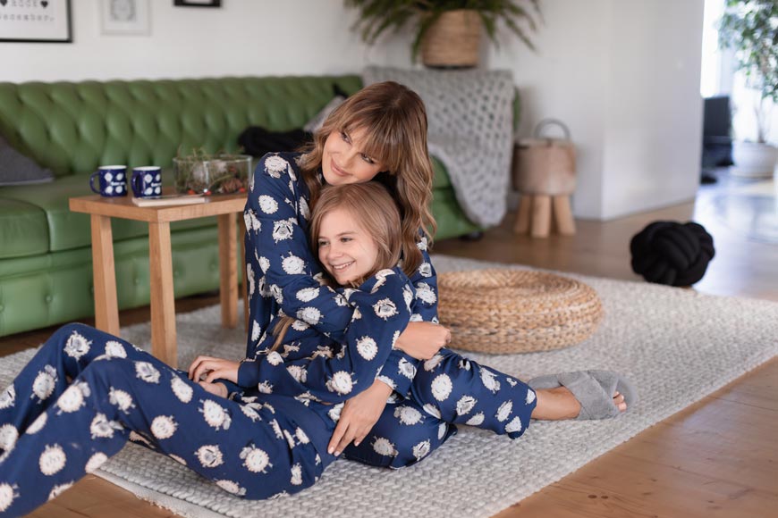 Majka i ćerka u istim pidžamama zagrljene na podu